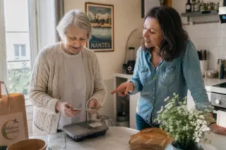 Senior woman and her daughter unpacking a meal delivery in a homely Nantes kitchen, morning light, natural candid interaction.
